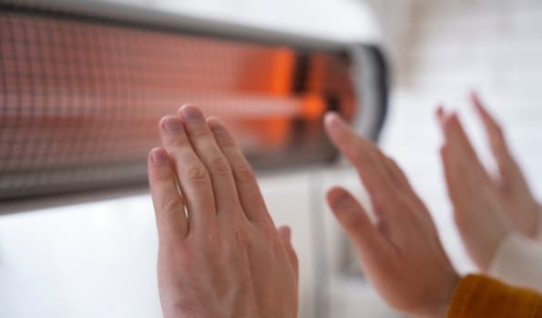 Hands reaching up to a heating radiato