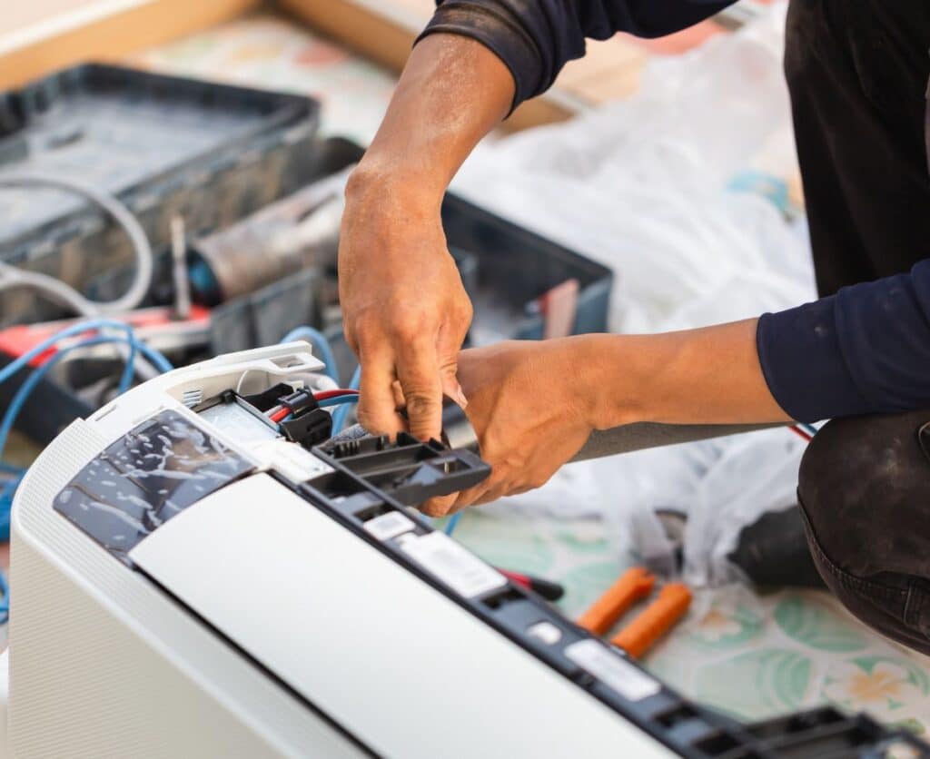 A man repairing a white air conditioner.